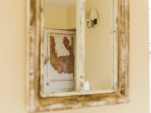 A mirror reflecting a door with peeling paint and a wall-mounted light fixture. - The Admiral's Home (Whitehaven)