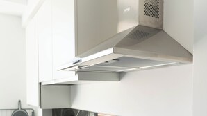 Een moderne keuken met een zwart marmeren aanrecht, roestvrijstalen apparatuur en witte kasten.