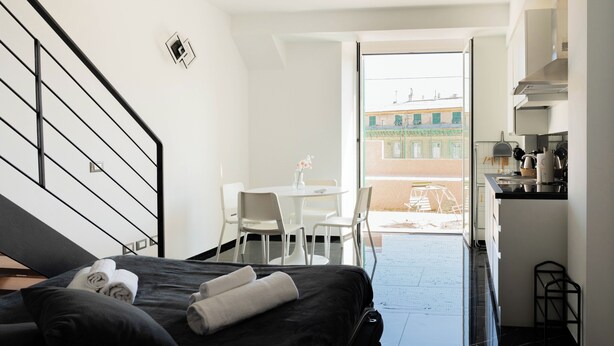 Hotelkamer met een bed, een tafeltje met stoelen, een kitchenette en uitzicht buiten.