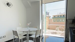 Een moderne kamer met een balkon, een eettafel met stoelen en uitzicht op gebouwen.
