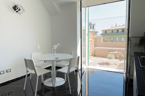 A modern room with a balcony, a dining table with chairs, and a view of buildings outside. - ✨ Apartment in the center, quiet and well served by public transportation (Genova)