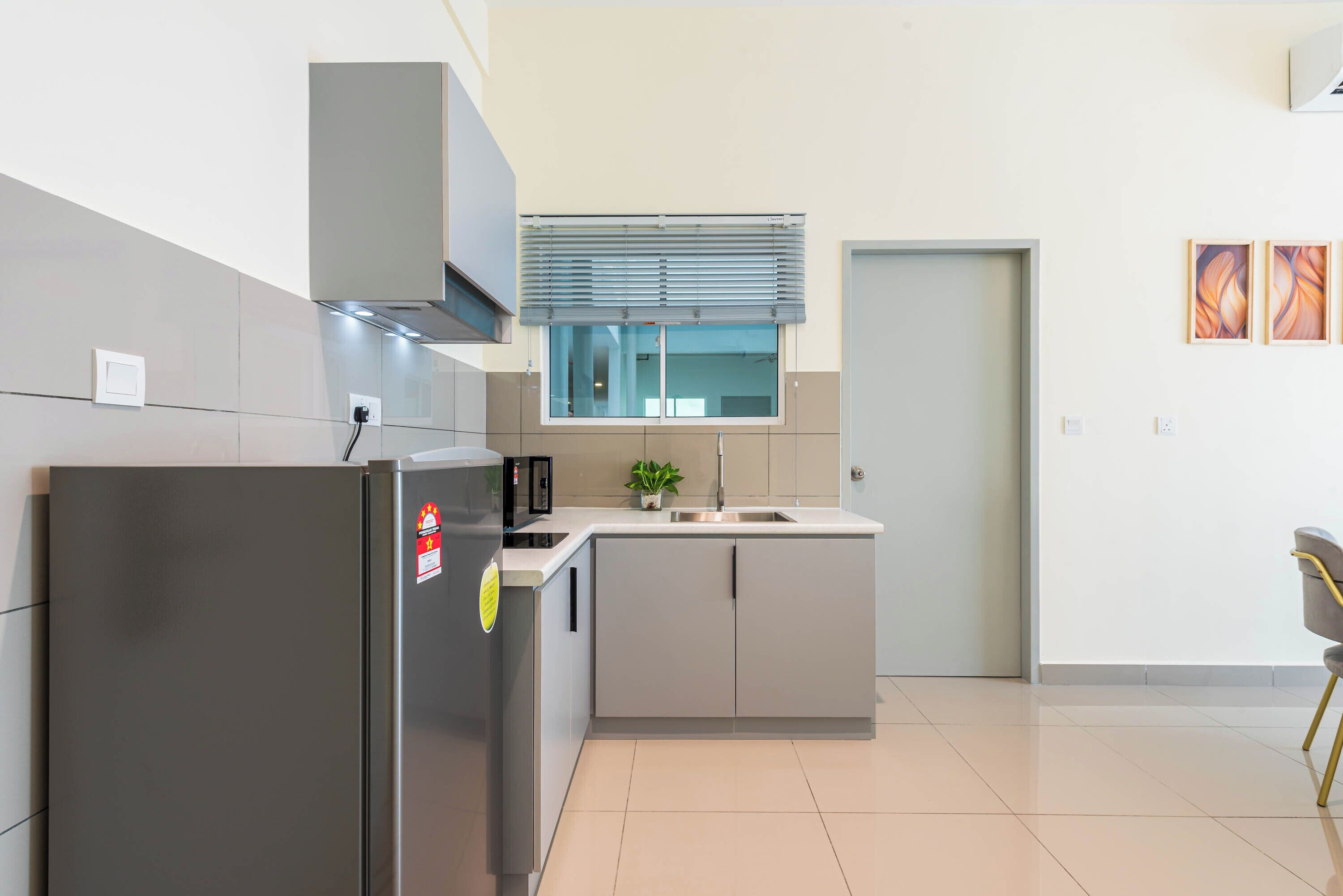 Een moderne keuken met een inbouwkoelkast, een spoelbak en een raam met zonwering.