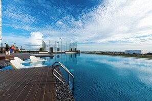 Una piscina al aire libre, sillones reclinables de piscina