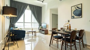 Una sala de estar moderna con un sofá, una mesa de comedor, sillas, una lámpara, un televisor y un cuadro en la pared.