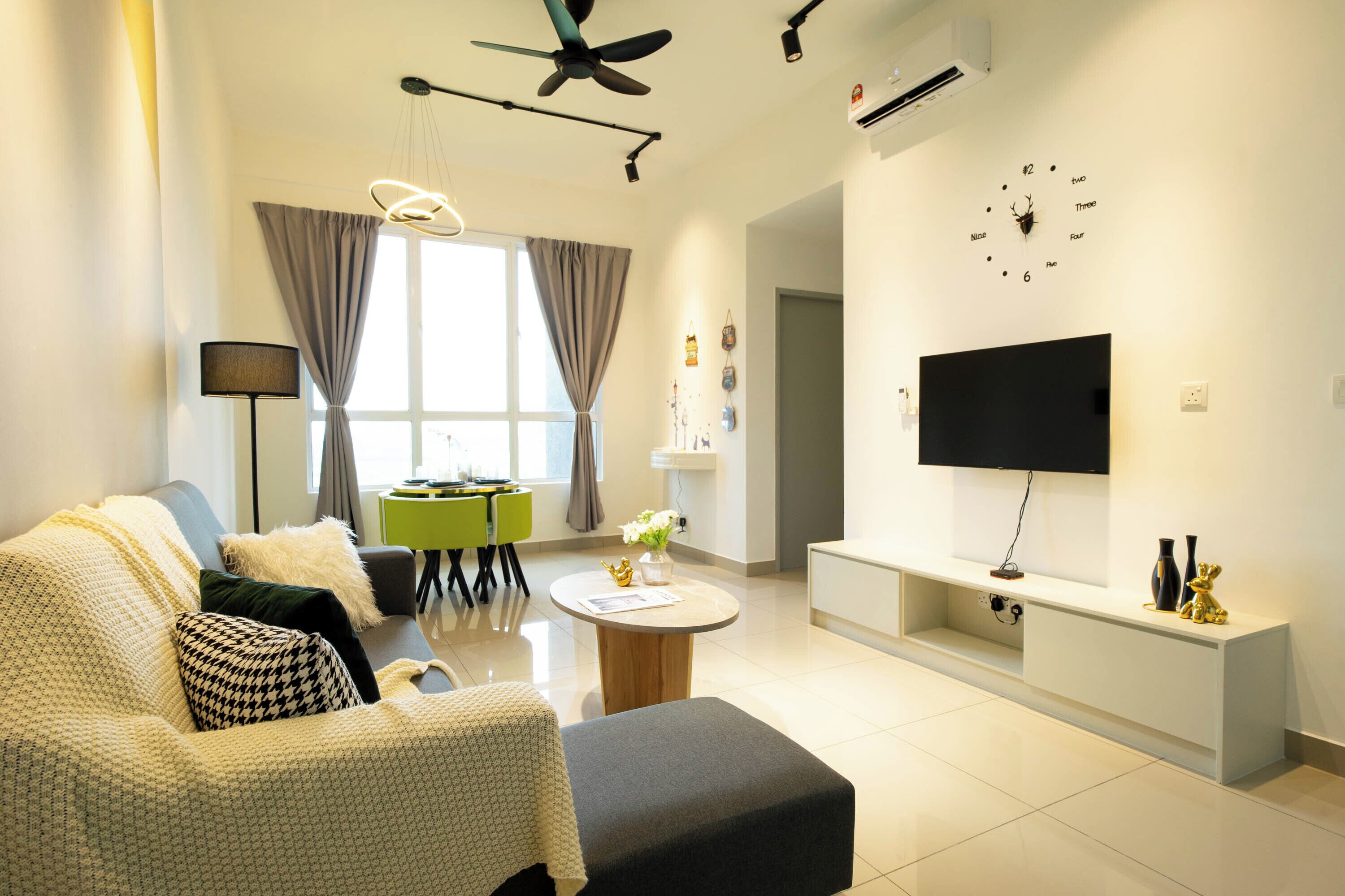 En moderne stue med sofa, sofabord, fladskærms-tv, loftventilator og spiseområde med bord og stole.