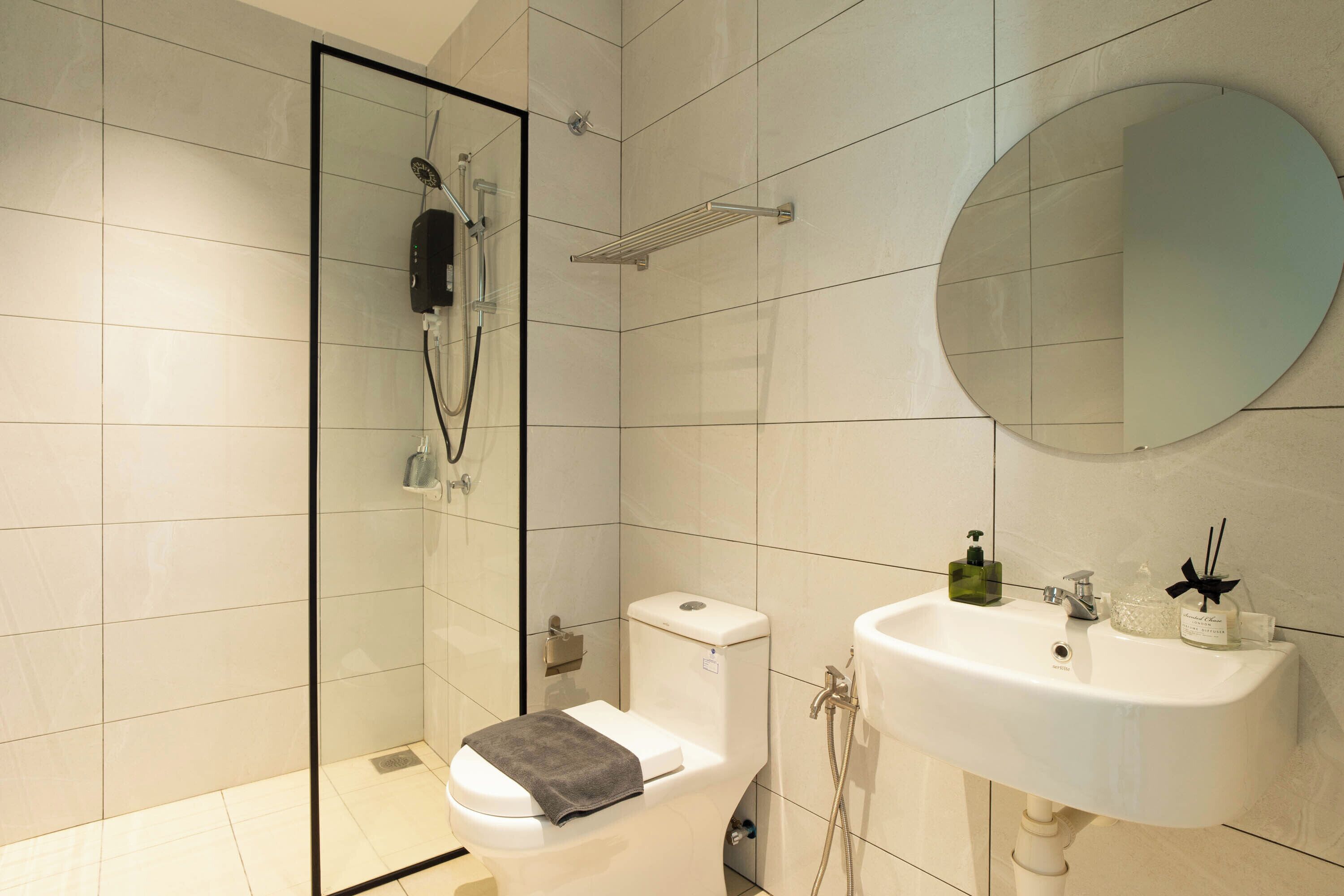 Une salle de bain moderne avec une douche à parois de verre, des toilettes, un lavabo et un miroir.