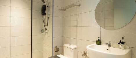 Une salle de bain moderne avec une douche à parois de verre, des toilettes, un lavabo et un miroir.