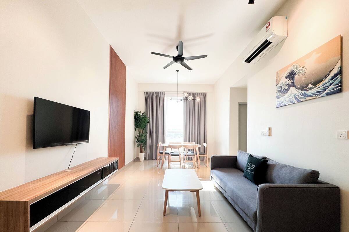 A modern living room with a flat-screen TV, a ceiling fan, a dining area with a table and chairs, and a sofa.