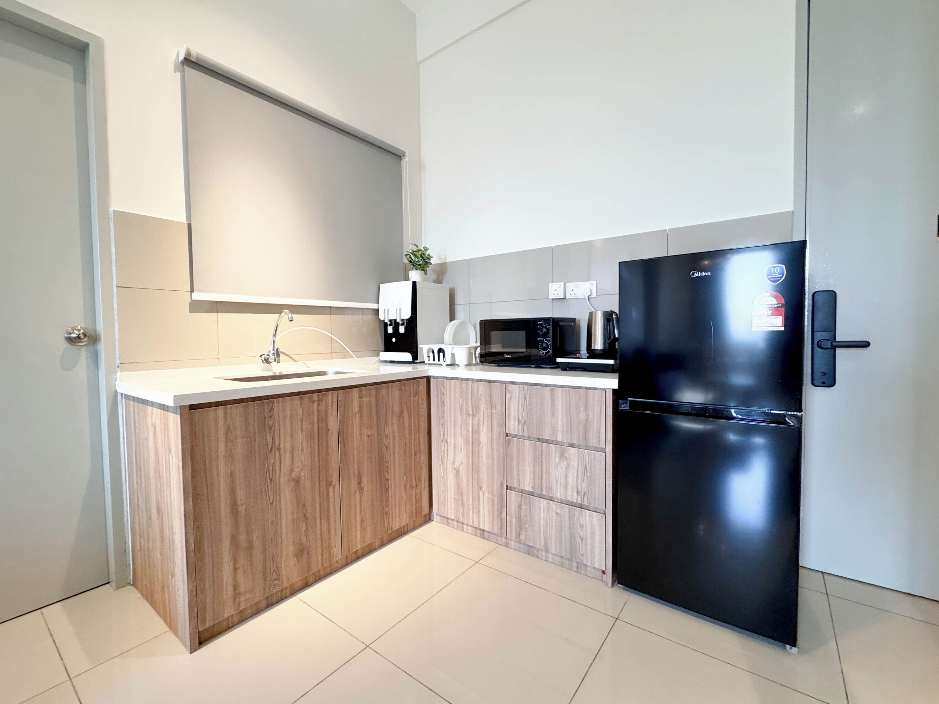 Een moderne keuken met een inbouw kookeiland, een zwarte koelkast, een magnetron en een koffieapparaat.