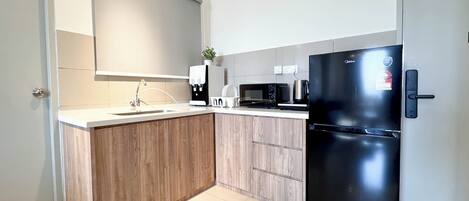 Een moderne keuken met een inbouw kookeiland, een zwarte koelkast, een magnetron en een koffieapparaat.