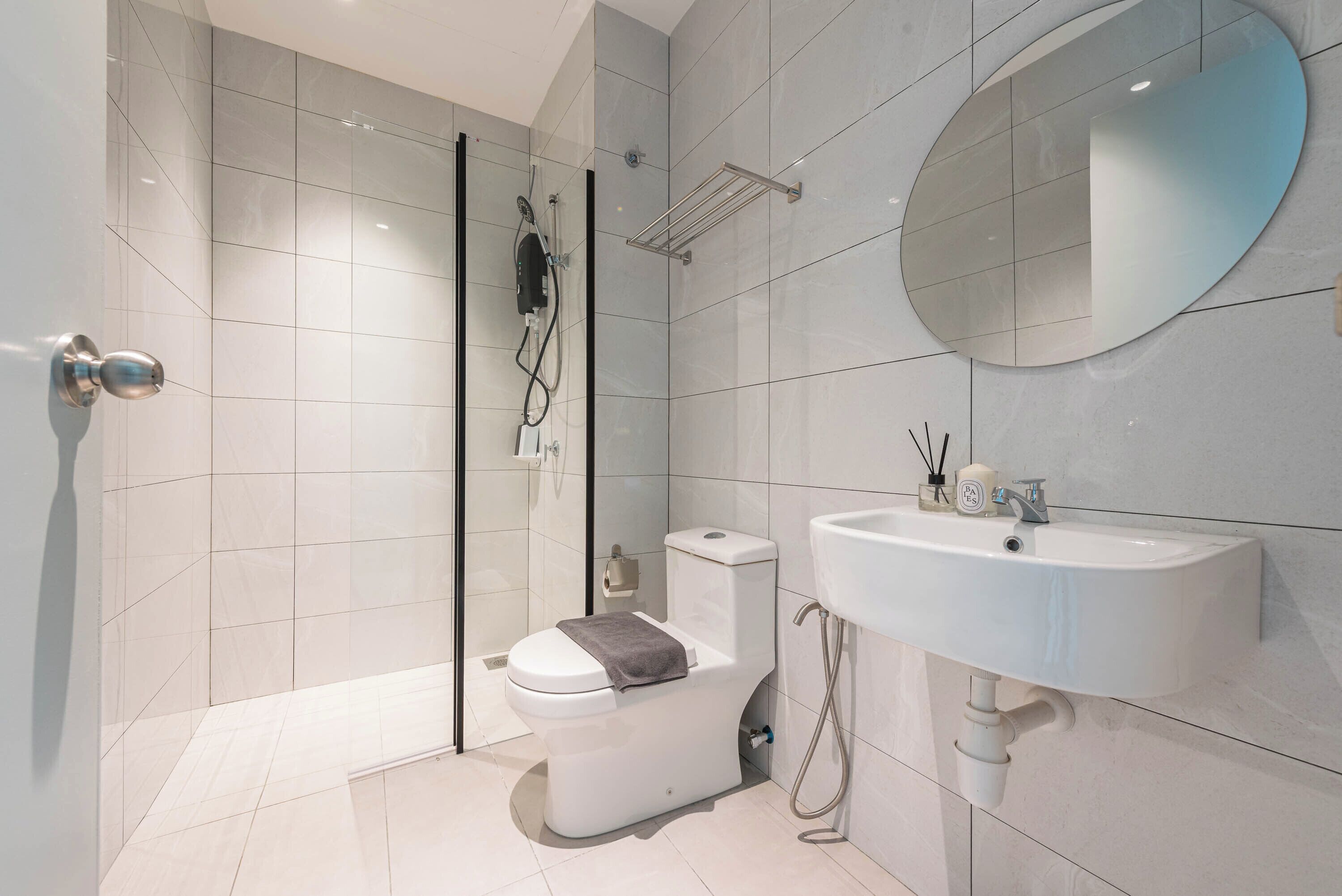 A modern bathroom with a toilet, shower, sink, and a large mirror.