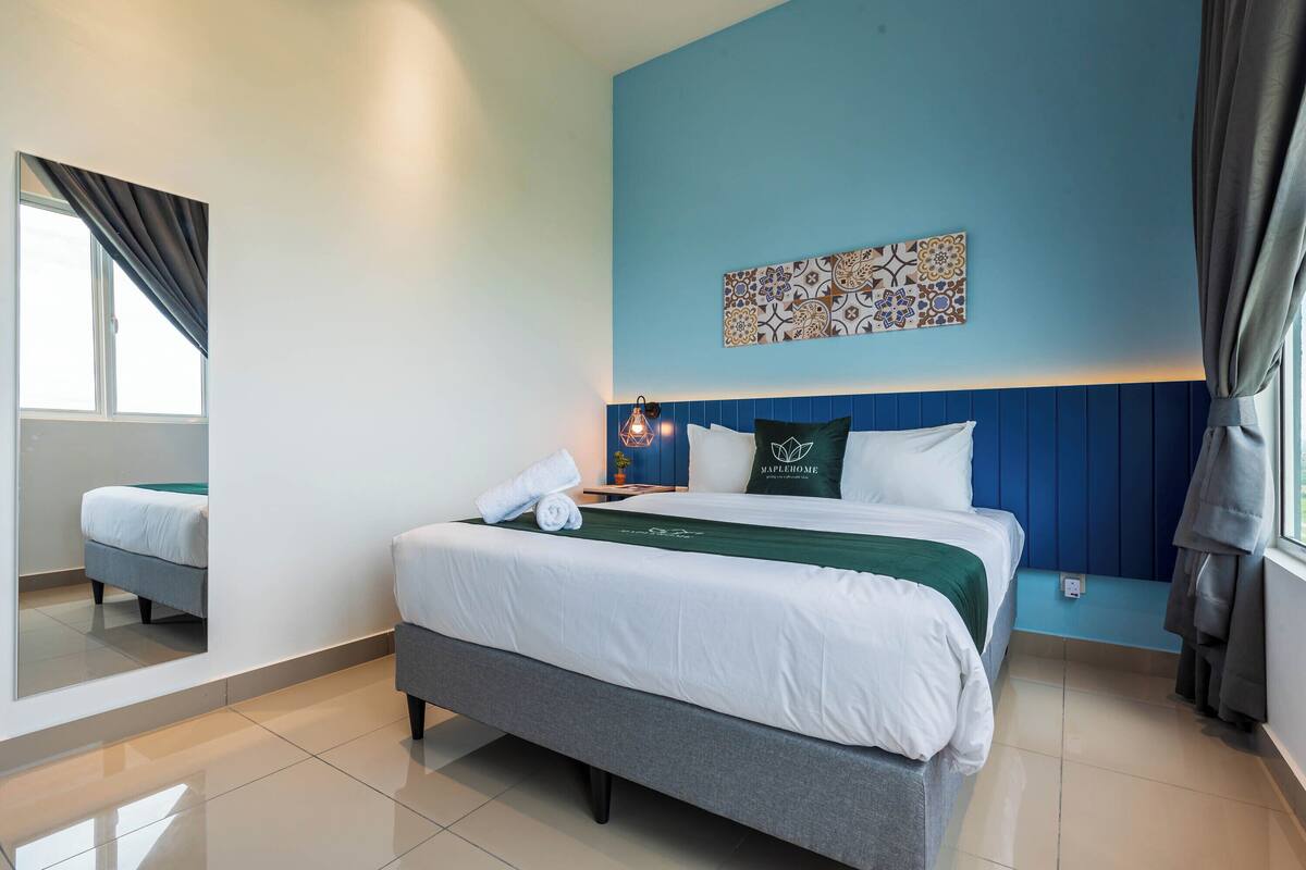 A hotel room with a bed, a nightstand, a wall-mounted artwork, and a window with curtains.