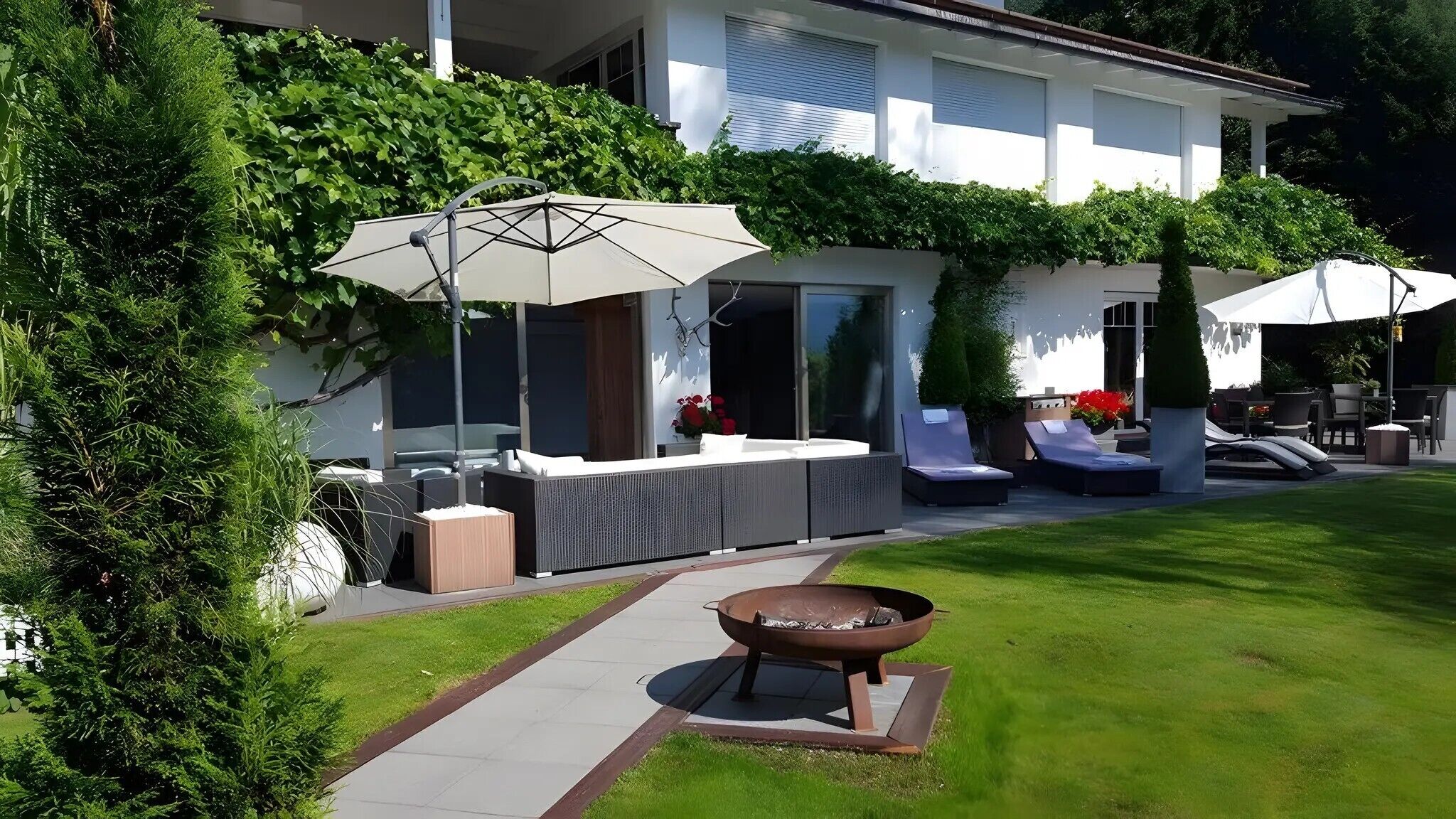 A modern outdoor patio with seating, a fire pit, and umbrellas.