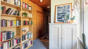 Un pasillo revestido de madera con estanterías, un armario blanco y un cuadro con un paisaje nevado.
