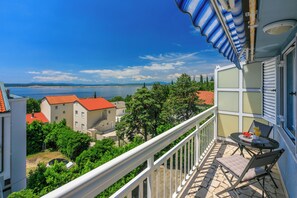 A balcony with a table and chairs, overlooking a body of water and buildings. - Well-kept apartment with sea view, balcony and quiet location near the sea (Dramalj)