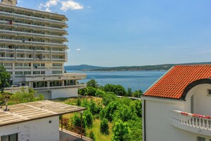 A multi-story building with balconies, a view of the sea, and a red-tiled roof. - Well-kept apartment with sea view, balcony and quiet location near the sea (Dramalj)