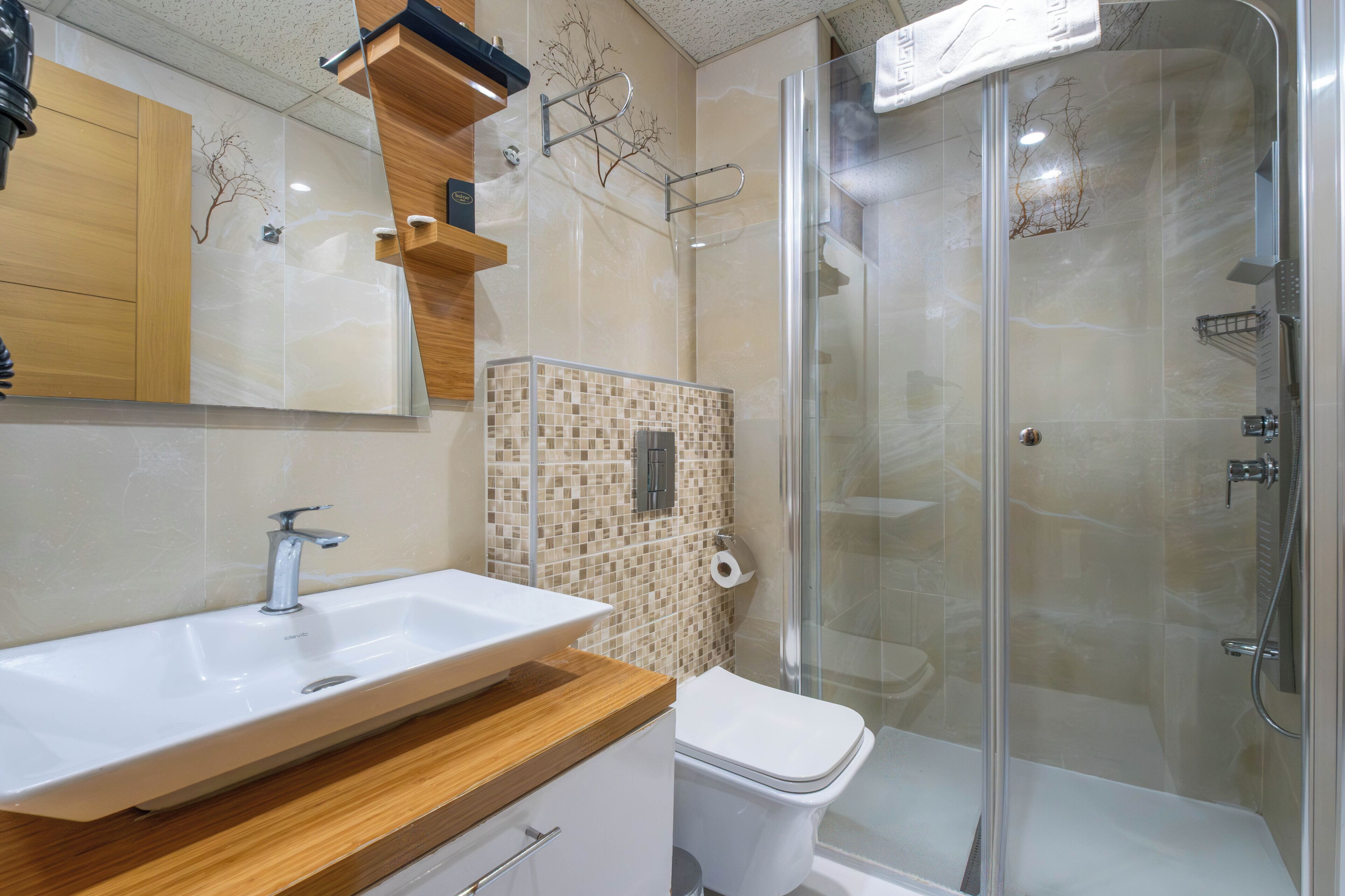 Un baño moderno con lavamanos, inodoro y ducha envuelta en vidrio.
