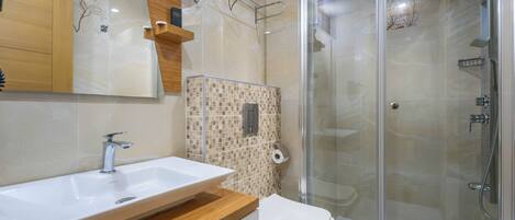 Un baño moderno con lavamanos, inodoro y ducha envuelta en vidrio.