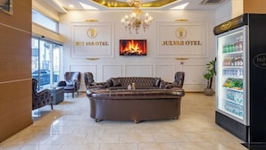 Un hall de hotel con un amplio sofá de cuero, un candelabro, una chimenea y un refrigerador con bebidas.