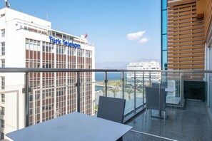 Un balcón con mesa y sillas, vista al mar y un edificio con la señalización 'Türk Telekom'.