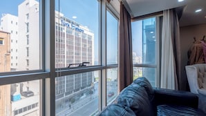 Una habitación con un ventanal grande, un sofá de cuero y vistas a un edificio con el rótulo 'Türk Telekom'.