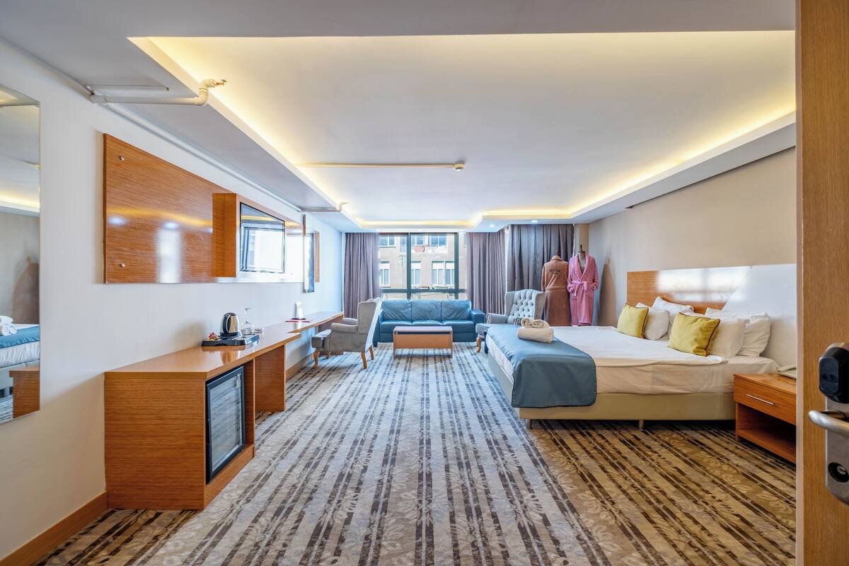 A hotel room with a bed, a desk, a chair, a TV, and a large window.