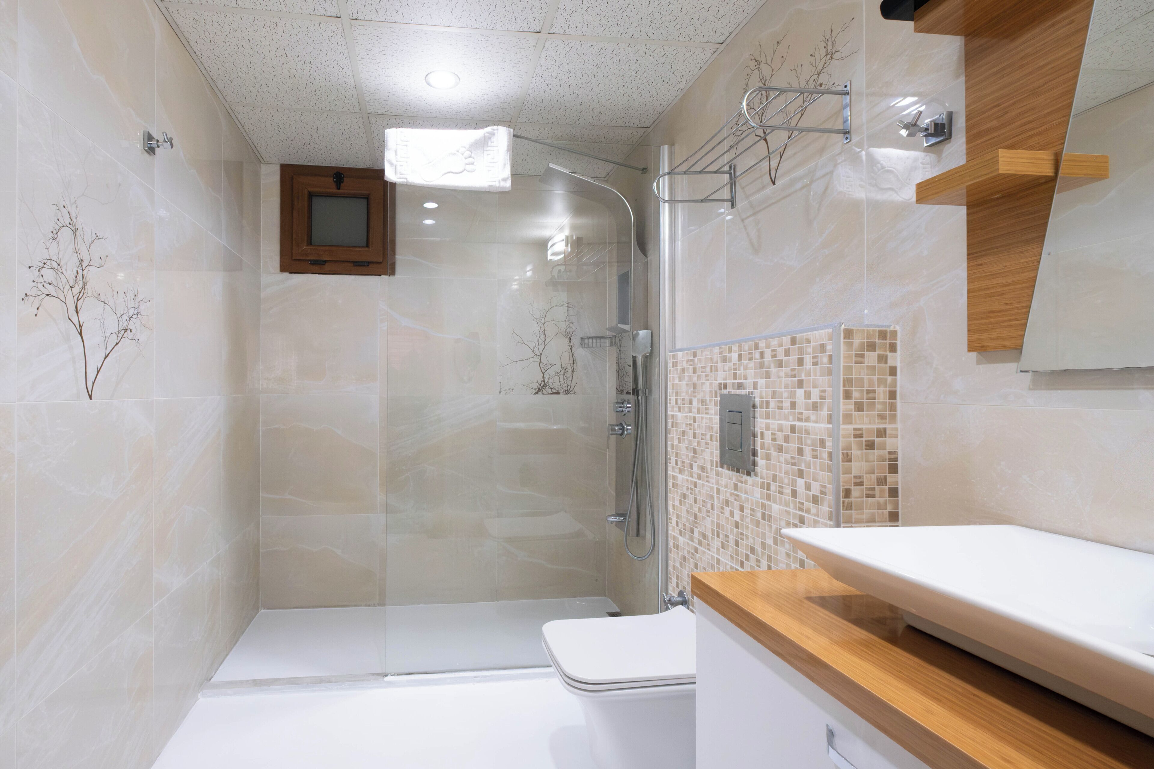 Une salle de bain moderne avec une douche à l’italienne en verre, une baignoire blanche et un meuble-lavabo en bois.