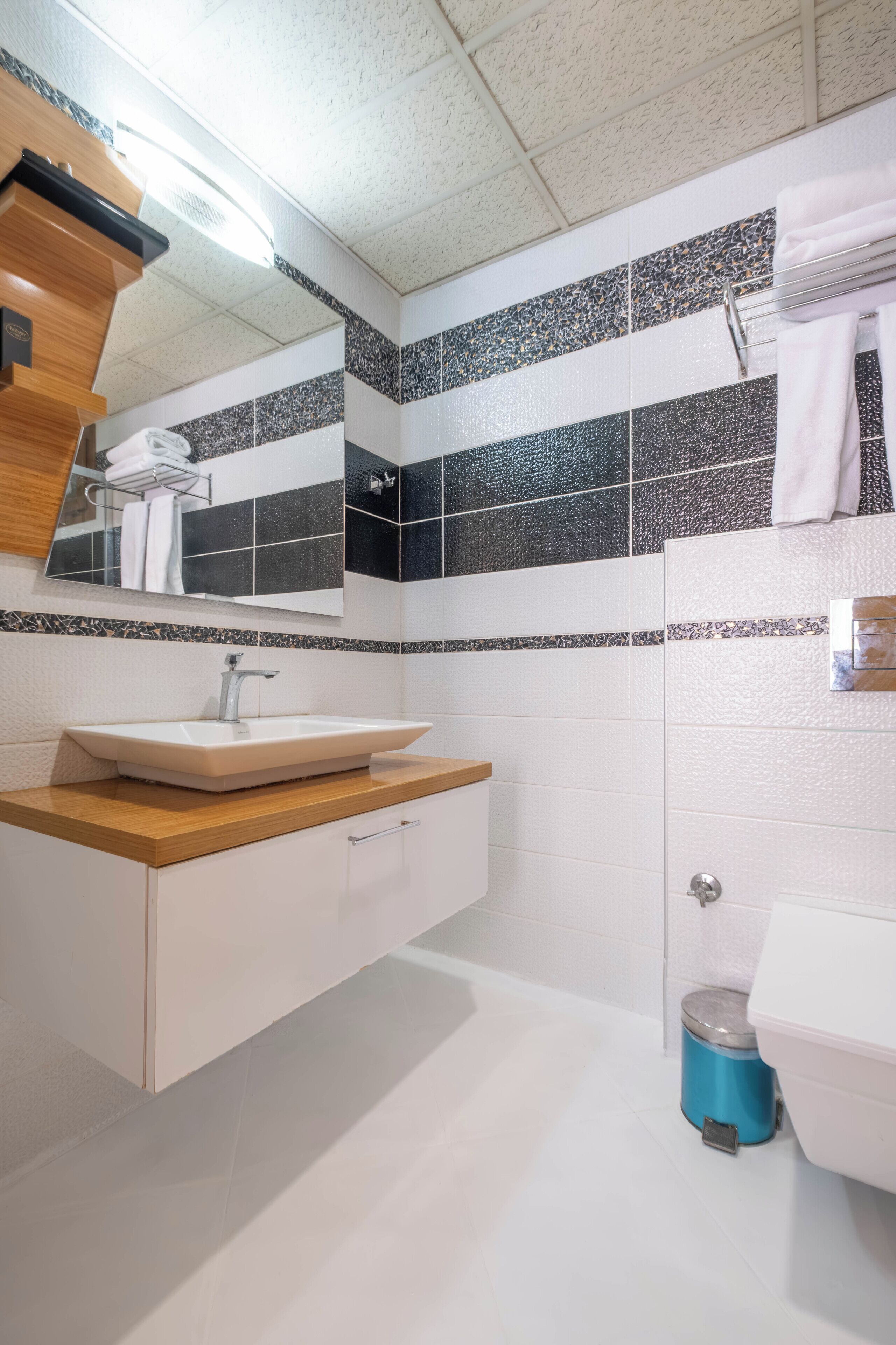 A modern bathroom with a white sink, wooden countertop, and a mirror above it.