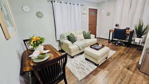 Un salon comprenant un canapé, un pouf, une table à manger et des chaises.