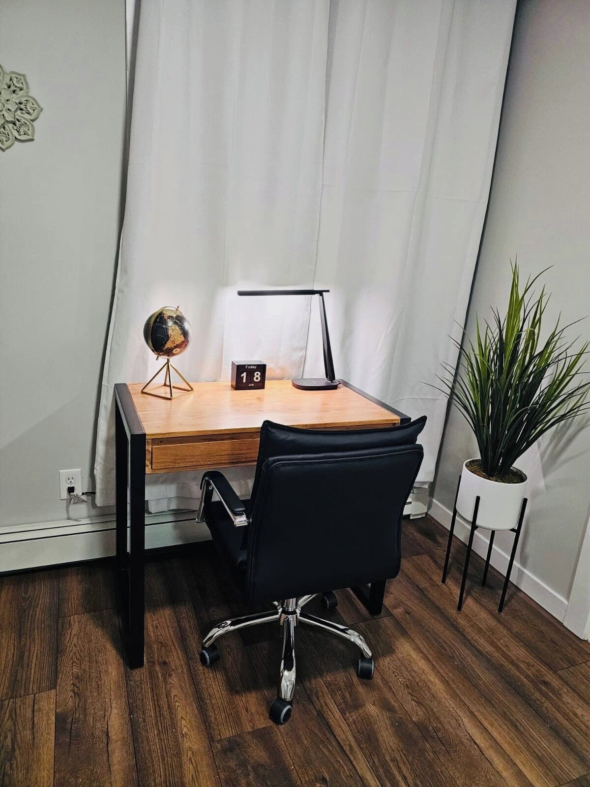 A small office desk with a globe, a desk lamp, and a calendar.