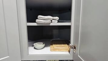 A kitchen with a white cabinet, a sink, and a countertop with a cutting board and a bowl.