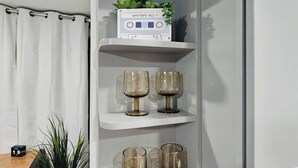 Une étagère blanche ornée d’objets décoratifs, notamment un lecteur de cassettes, deux statuettes d’oiseaux dorées et trois vases en verre.