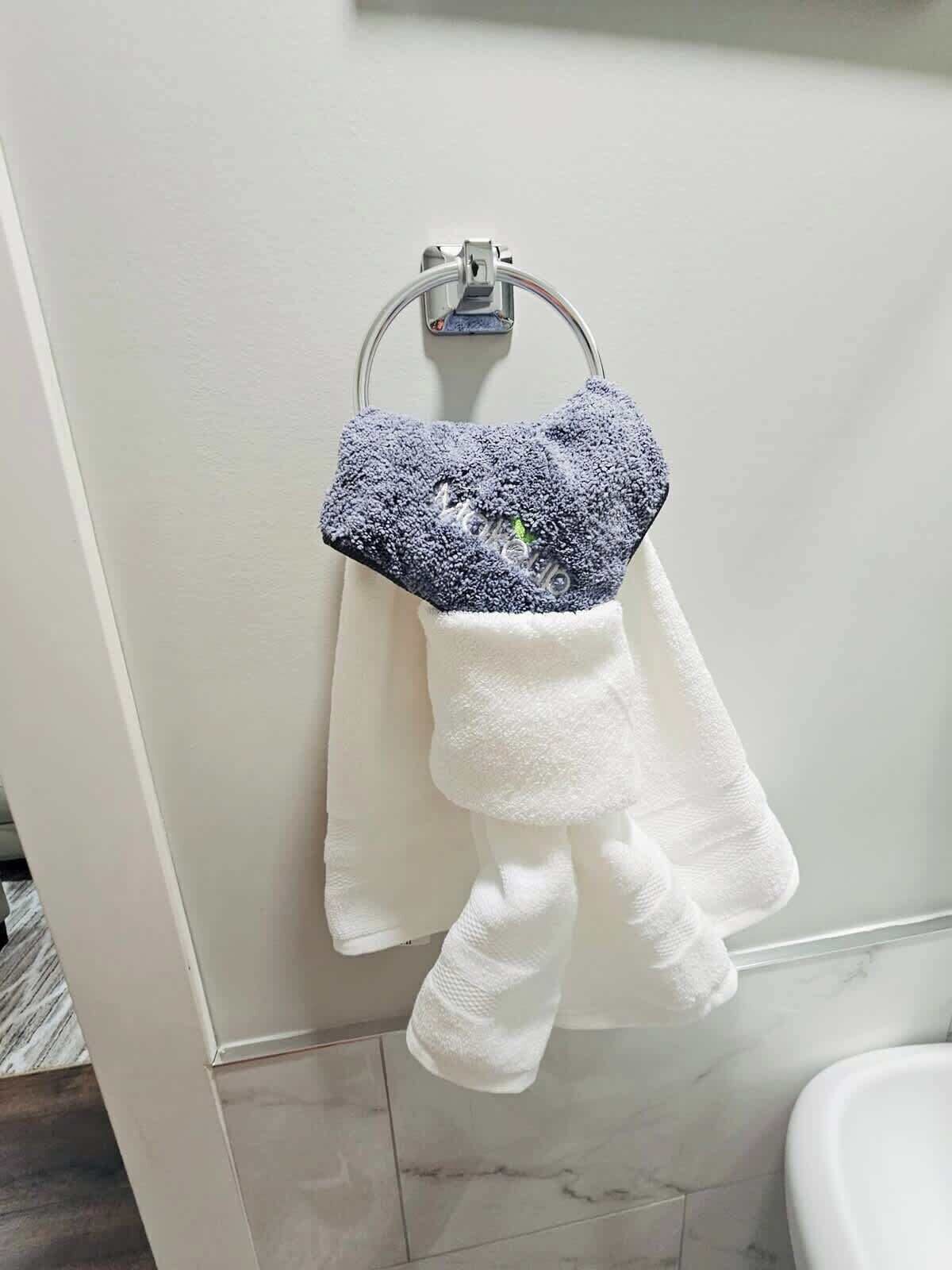 A bathroom with a white towel rack holding a white towel and a blue towel.