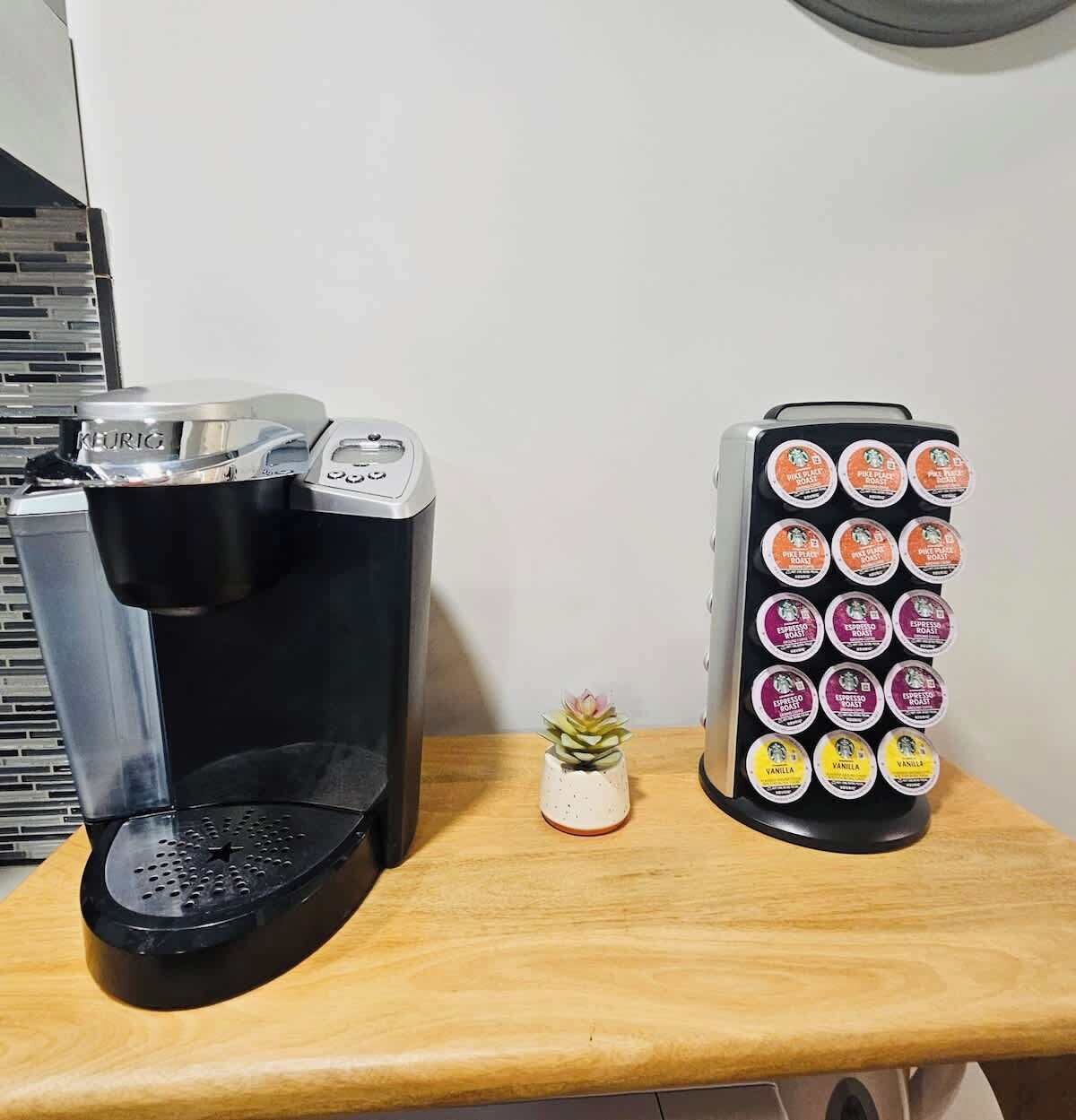 A coffee maker and a coffee pod holder on a wooden surface.
