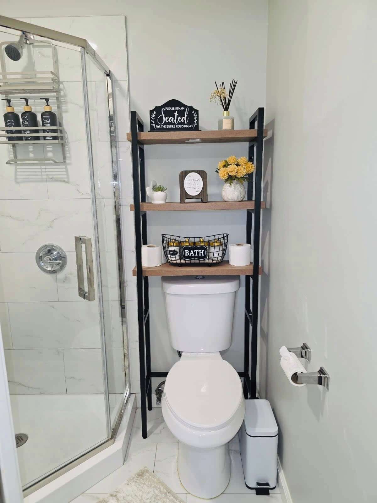 Un bany amb plat de dutxa de vidre, vàter, bidet i prestatgeries amb productes de tocador.
