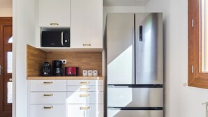 Una cocina con un refrigerador de acero inoxidable, un microondas y una cafetera sobre la encimera.