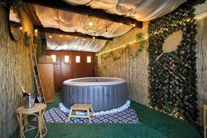 Un bain à remous dans une pièce aux murs en bambou, avec une porte en bois et un petit tabouret en bois.