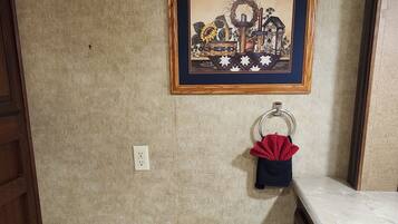 A small bathroom with a toilet, a trash bin, a sink, and a framed picture on the wall.
