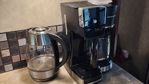 A kitchen with a coffee maker, a glass carafe, and a tiled backsplash. - Beautiful 5th wheel with 4 slides in point blank (Point Blank)
