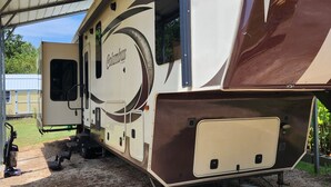 A recreational vehicle with a covered area, a door, and a window.