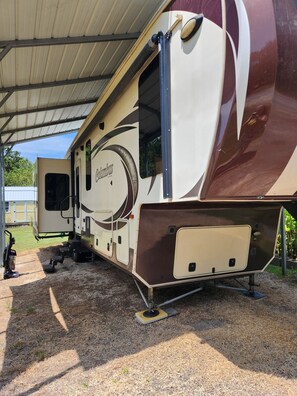 A recreational vehicle with a covered area, a door, and a window.