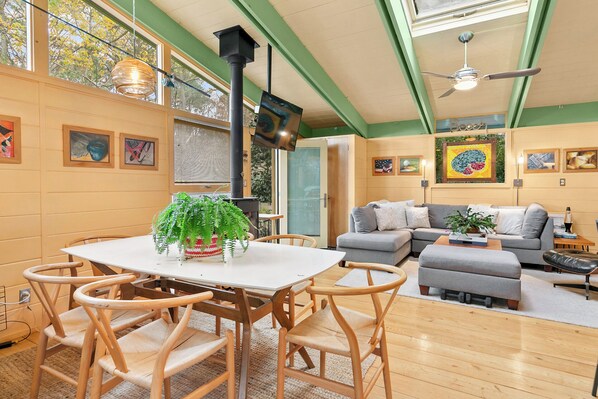 A dining area with a white table and wooden chairs, a sofa, and a ceiling fan.