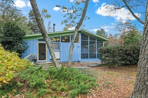 A blue house with a porch, surrounded by trees and a yard.