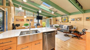 Een moderne keuken met een vaatwasser, houten kastjes en een zithoek met een bank en stoelen.