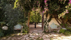 A stone pathway leading to a gate with a tiled wall and a bench. - Tenuta Donna Vittoria Bouganville Apartment with Mountain View, Wi-Fi & Air Conditioning (Trapani)