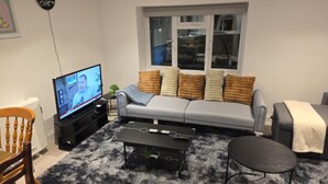 A living room with a sofa, a coffee table, a TV, and a window. - Stylish Stay in Brighton: London Road Gem (Brighton and Hove)