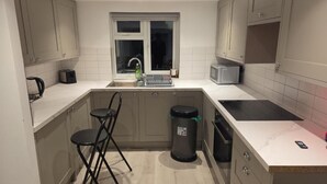 A compact kitchen with a sink, a microwave, a kettle, and a small window. - Stylish Stay in Brighton: London Road Gem (Brighton and Hove)