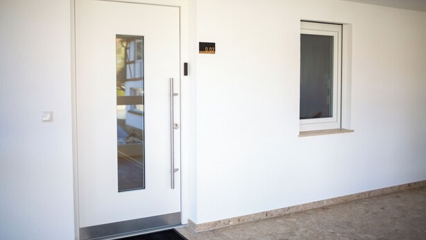 A white door with a glass panel, a small window, and a doorbell. - BEST STAY Rhönzauber Dietershausen (Künzell)