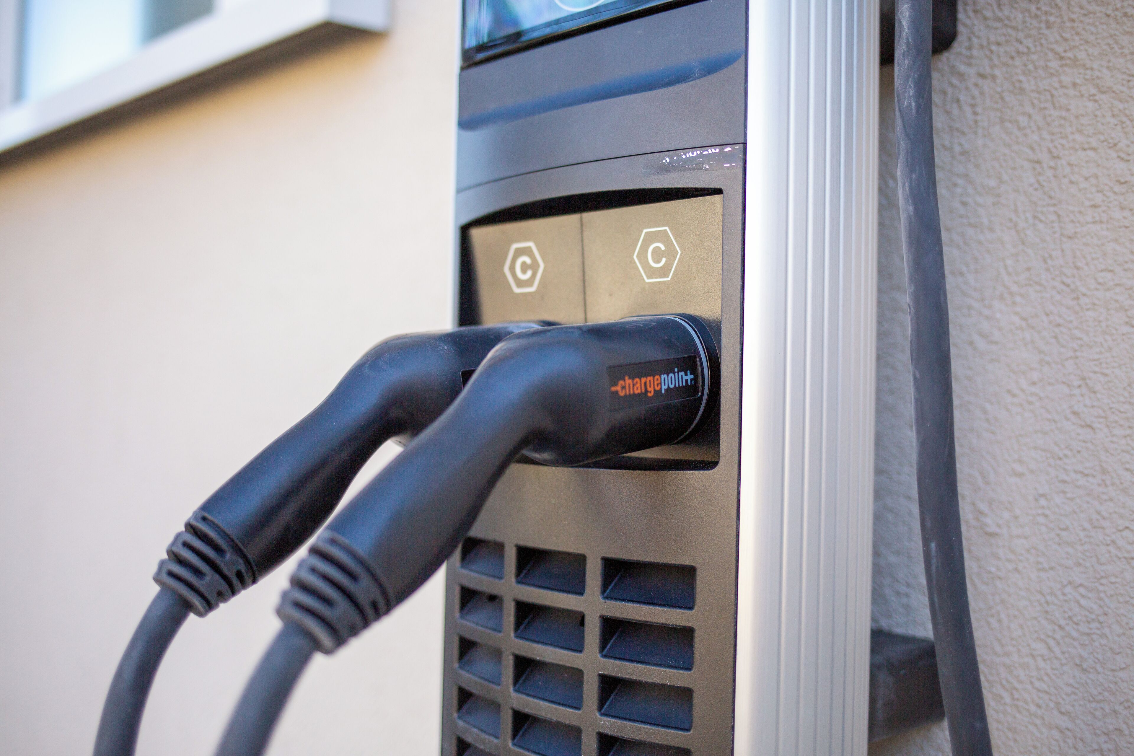 Une borne de recharge dotée de deux câbles branchés, d’une étiquette indiquant « chargepoint » et d’un symbole hexagonal.