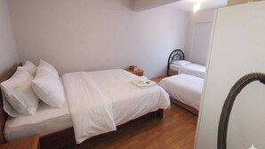 A bedroom with two beds, a wooden floor, a nightstand, and a mirror. - Quiet and Comfortable in Sinop Karakum Site 2 (Sinop)